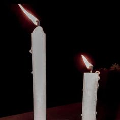 two white candles sitting on top of a table