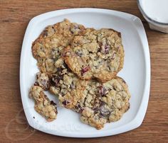 three oatmeal cookies on a white plate next to a glass of milk