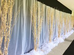 the wall is covered with white fabric and gold branches are lined up along it's sides