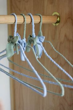 the clothes hangers are made from wood and have blue bows on them, along with green ribbons