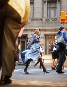 people are walking down the street in front of a building