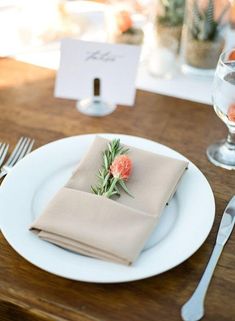 a place setting with napkins, silverware and flowers on the plate in front of it