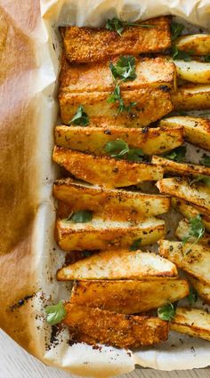 baked potato wedges with herbs and seasoning in a baking dish on a wooden table