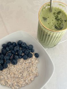 a bowl of oatmeal with blueberries next to a glass of green smoothie