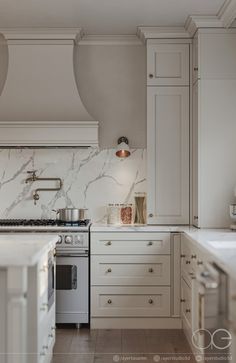 a kitchen with white cabinets and marble counter tops, along with a stove top oven