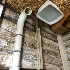 a white toilet sitting on top of a wooden floor next to a trash can and paper dispenser