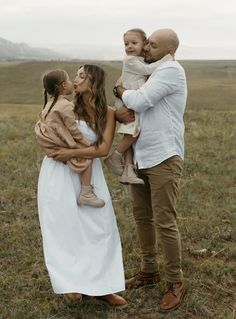 a man holding a baby while standing next to two women and a child in a field