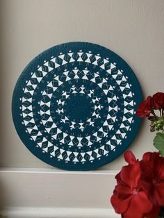 a blue and white plate sitting on top of a counter next to a vase with red flowers