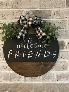 a welcome sign hanging on the side of a brick wall that says, welcome friends