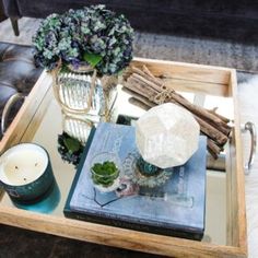 a tray with candles, flowers and other items on it sitting on a leather couch