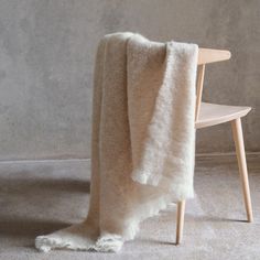 a white blanket sitting on top of a wooden chair