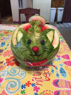 a watermelon carved to look like a cat's face with blue eyes