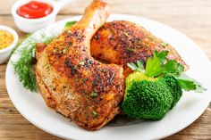 a white plate topped with chicken and broccoli next to dipping sauce on a wooden table