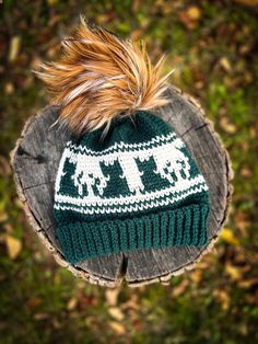 a green and white knitted hat sitting on top of a tree stump