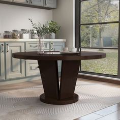 a dining table in front of a large window with an open kitchen area behind it