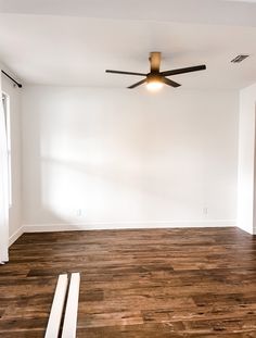 an empty room with hard wood flooring and ceiling fan