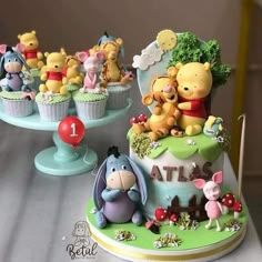 winnie the pooh birthday cake and cupcakes on a table with other figurines