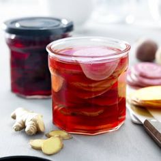 a jar filled with liquid sitting on top of a table next to sliced fruit and vegetables