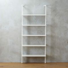 a white book shelf against a wall in an empty room with wood floors and wooden flooring