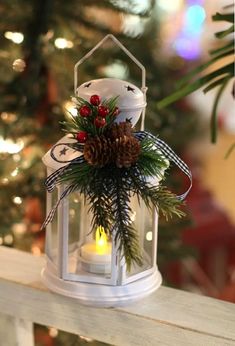 a white lantern filled with pine cones and berries