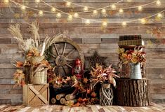 an arrangement of autumn decorations on a wooden floor with lights strung above it and pumpkins in the background