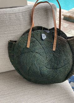 "You loved the Tiana Tote but some requested a smaller version of this 100% eco friendly bag. Only natural sustainable materials are used for this hand crocheted raffia tote. Available in a beautiful earthy that has been colored using natural vegetable dyes, variations in color make each bag unique.  The handles are natural leather, and the button closure is handcrafted from carved Zebu horn (Madagascar's cow). It's a handbag, beach bag, shopper, or just about anything you want it to be. Nothing goes to waste. AND your purchase helps the female artisans in Madagascar who hand-craft these beautiful items. Slight variations in size and color and the hand carved zebu buckle make your bag truly one if a kind! Measures ~ 18\"x 18\". Handle has ~8\" drop." Eco Friendly Bags, Raffia Bag, Women Artisans, Sustainable Materials, New Bag, Natural Leather, Hand Crochet, Beach Bag, Horn