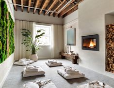 a living room filled with lots of white pillows and blankets next to a fire place