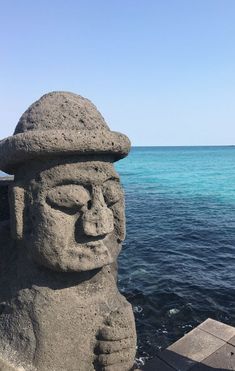 a stone statue sitting on top of a beach next to the ocean