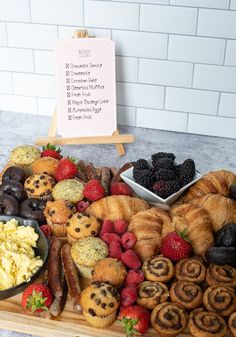 an assortment of pastries and desserts displayed on a wooden platter in front of a sign