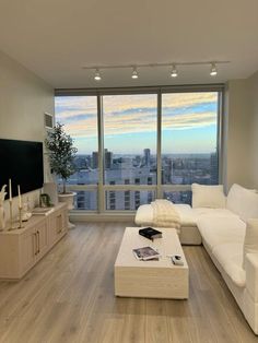 a living room with white furniture and large windows looking out on the cityscape