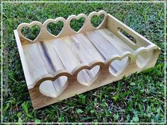 a wooden tray with hearts on it sitting in the grass