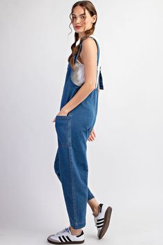 Mineral washed solid sleeveless jumpsuit featuring adjustable straps, a scoop neckline, two open front pockets and is a straight leg style. Model is 5'9" and wearing a small.75%COTTON 23%POLYESTER 2%SPANDEX Medium Wash Denim Overalls With Side Pockets, Relaxed Fit Medium Wash Overalls With Adjustable Straps, Medium Wash Overall Jumpsuits And Rompers With Side Pockets, Spring Denim Overalls In Solid Color, Solid Denim Overalls Jumpsuit, Solid Denim Overalls, Sleeveless Washed Overalls For Summer, Sleeveless Cotton Washed Jumpsuits And Rompers, Spring Denim Overalls