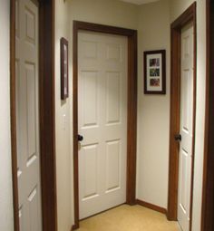 an empty hallway with two doors and pictures on the wall