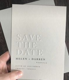 someone holding up some white cards with the words save the date written on them in silver foil