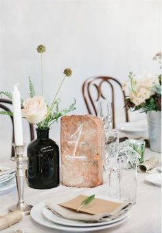 the table is set with black and white plates, silverware, candles and flowers