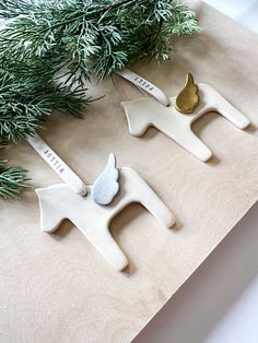 three ceramic ornaments are sitting on a table next to a pine branch and some other decorations