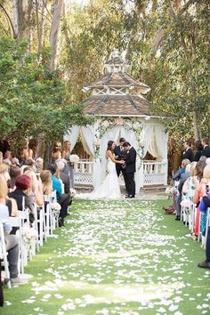 a bride and groom standing at the end of their wedding ceremony in front of an outdoor gazebo