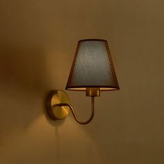 a wall light with a lamp on it in a room that is painted yellow and has a brown shade