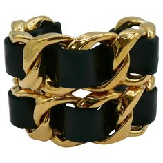 CHANEL by KARL LAGERFELD vintage iconic gold toned rigid chain cuff bracelet featuring woven black leather. Collection year n°23 (1988). VICTOIRE DE CASTELLANE era. Embossed CHANEL 2 3 Made in France. Indicative measurements : inner circumference approx. 18.85 cm (7.42 inches) / width approx. 5.5 cm (2.17 inches) / wrist opening approx. 3 cm (1.18 inches). Materials : Gold tone metal hardware / Leather. NOTES - This is a preloved vintage item, therefore it might have imperfections. - Colors may Gold Vintage Leather Bracelet, Gold Leather Cuff Bracelet For Formal Occasions, Formal Gold Leather Cuff Bracelet, Gold Leather Cuff Jewelry, Vintage Gold Leather Bracelet, Gold Leather Cuff Bracelet, Chanel Bangle, Gold Leather Bracelet, Vintage Chanel Jewelry