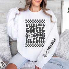 "Stay cozy and stylish on the sidelines with our personalized soccer mom crewneck sweatshirt! The front features a retro-inspired \"weekends, coffee, soccer, repeat\" text, perfect for every soccer mom out there. On the left sleeve, you'll find a design showcasing your kid's name and their jersey number, adding a special touch to this already unique piece. Whether you're cheering on your little star or running errands, this sweatshirt is a must-have for any soccer mom who wants to show off their pride in style. *All items are printed to order. They will ship out within 1 week from our printing partner.  We kindly ask for your understanding as you factor in both production and shipping.  *Care Instructions*  Please turn sweatshirt inside out and wash cold on delicate cycle to maintain its q White Long Sleeve Sweatshirt For Weekend, Weekend Crew Neck T-shirt With Letter Print, Sporty Letter Print Tops For Weekend, Weekend Letter Print Crew Neck T-shirt, Sporty Weekend Tops With Letter Print, Sporty Tops With Letter Print For Weekend, Sporty Cotton Tops With Letter Print For Weekend, Weekend Crew Neck T-shirt, Weekend White Crew Neck Sweatshirt