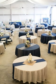 tables with blue and white linens are set up in a large tent for an event