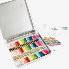 an open tin box filled with lots of different colored thread