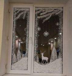 two glass windows decorated with christmas decorations and reindeers in the snow at night,