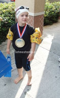 a little boy that is standing up with a medal on his neck and wearing a hat