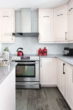 a kitchen with white cabinets and stainless steel stove top oven in the center of the room