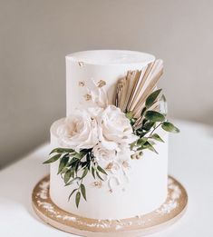 a white wedding cake with gold lettering and flowers