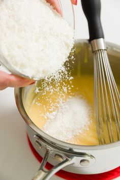 someone is adding sugar to the mixture in a saucepan with a whisk