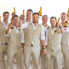 a group of men standing next to each other holding beer bottles in front of them