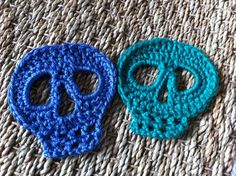 two crocheted sugar skulls sitting next to each other on top of a rug