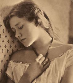 an old photo of a woman with her hands on her chest, leaning against the back of a couch